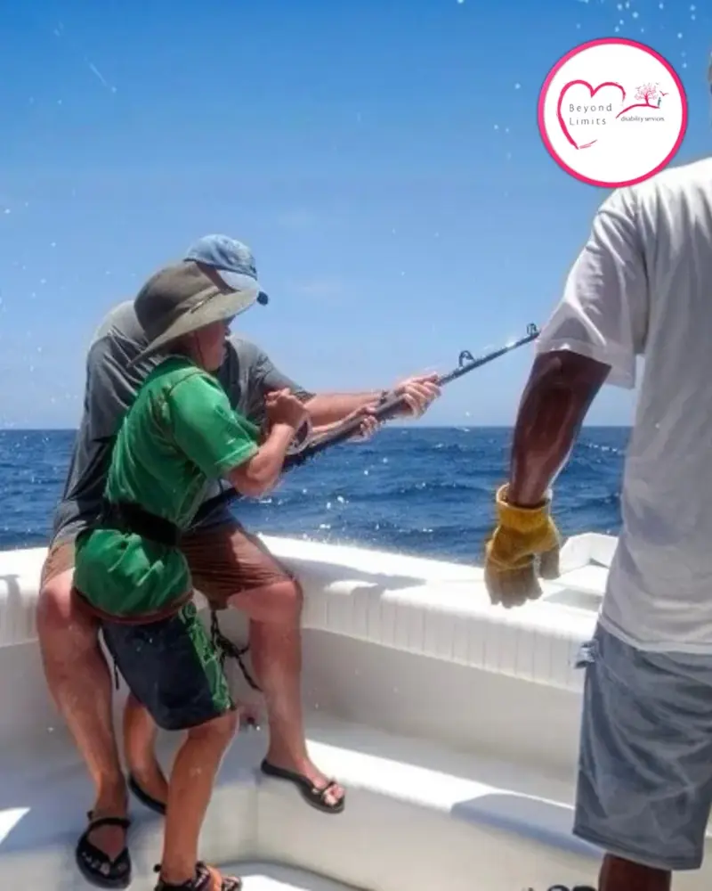A participant reeling in a fish on a boat trip with support workers