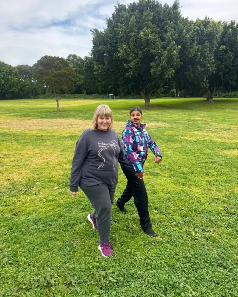Two participants walking together across a grassy park
